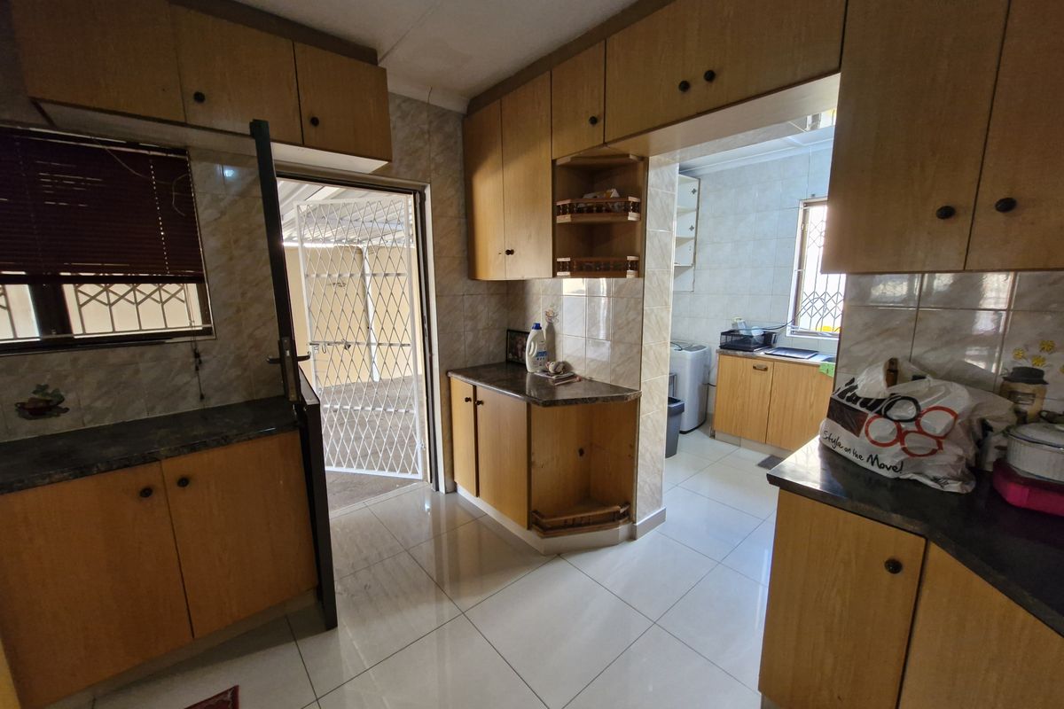 A functional kitchen featuring laminate cabinetry, tiled flooring, and direct access to an outdoor area secured with a metal gate.