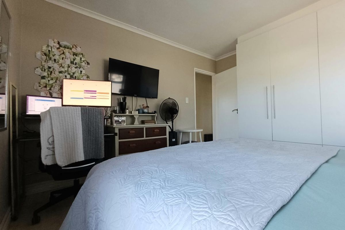 A functional bedroom featuring neutral wall tones, built-in white wardrobes, and coving detail, providing a practical space for rest and storage.