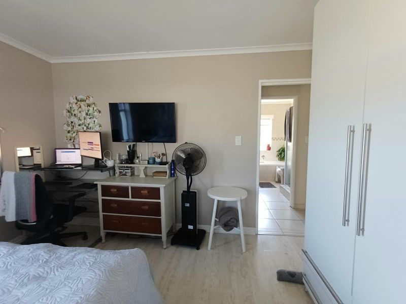 A bedroom featuring built-in wardrobes, laminate flooring, and direct access to an en-suite bathroom.