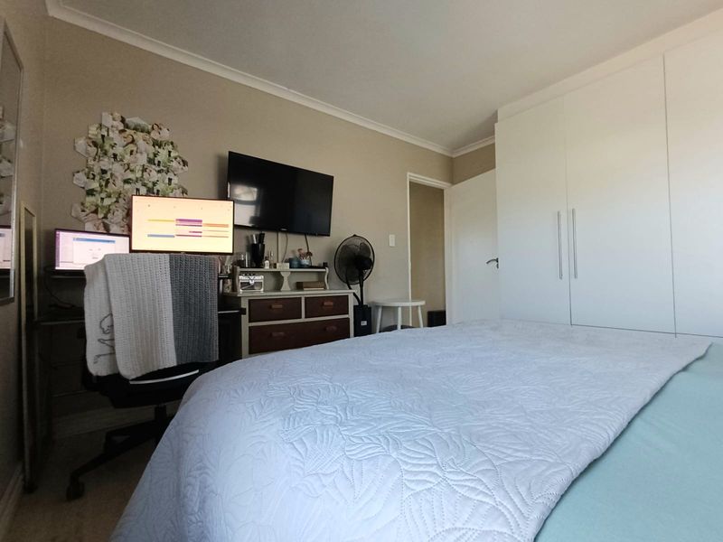 A functional bedroom featuring neutral wall tones, built-in white wardrobes, and coving detail, providing a practical space for rest and storage.