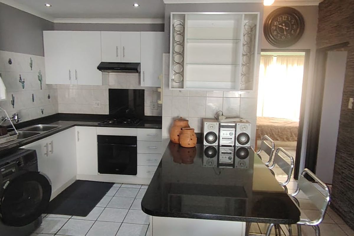 A functional kitchen featuring white cabinetry, black granite countertops, a built-in oven with gas hob, and a convenient breakfast bar area.