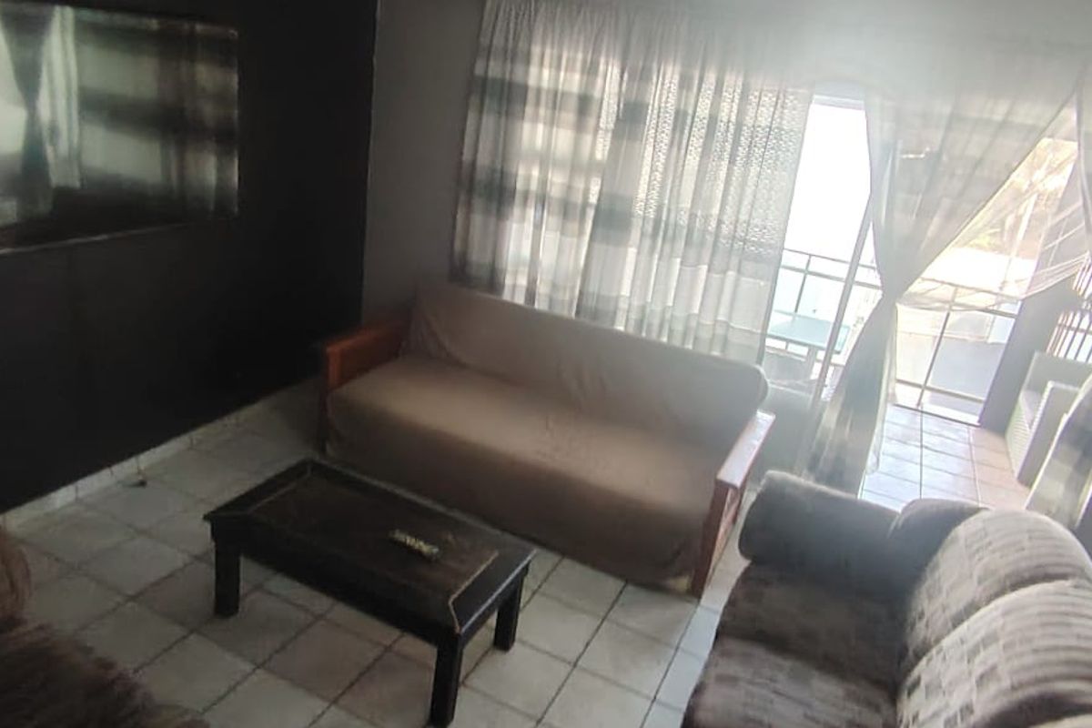 A living room featuring tiled flooring and a sliding glass door providing direct access to an outdoor balcony area.