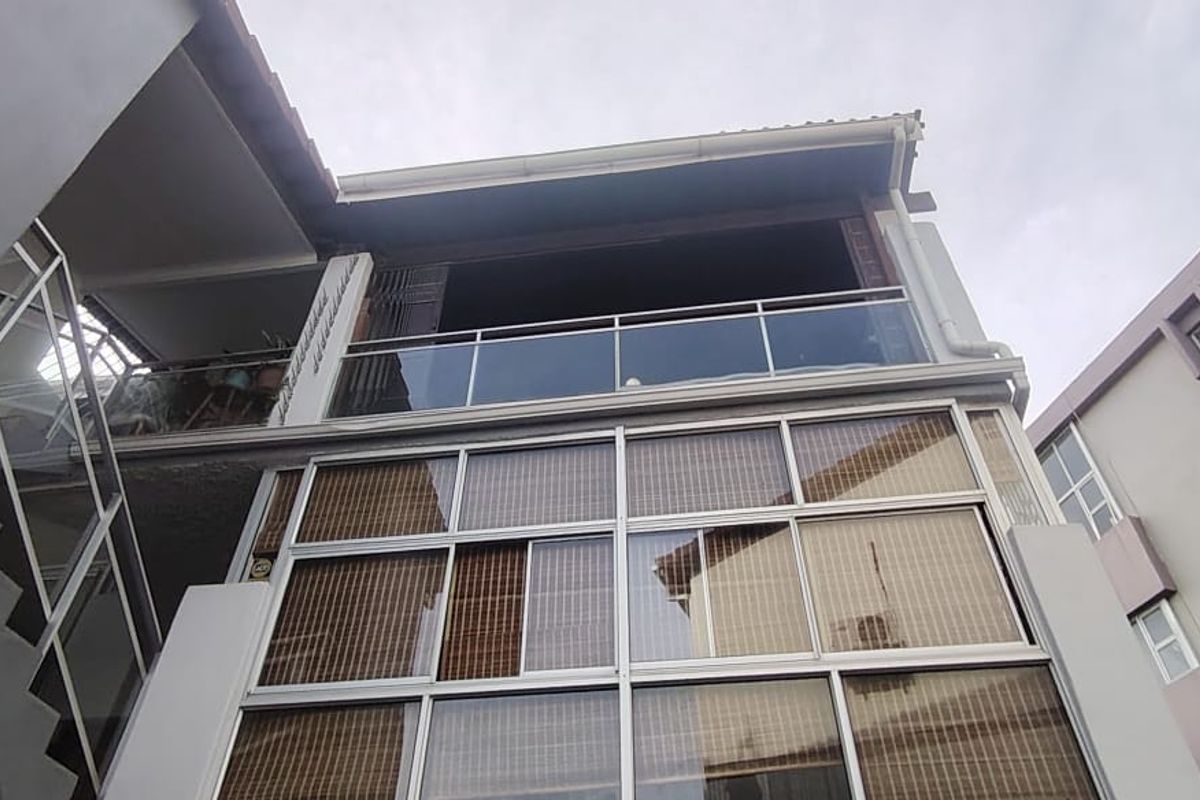 Low-angle view of the townhouse rear elevation featuring a glass balustrade balcony and multi-pane window configuration.