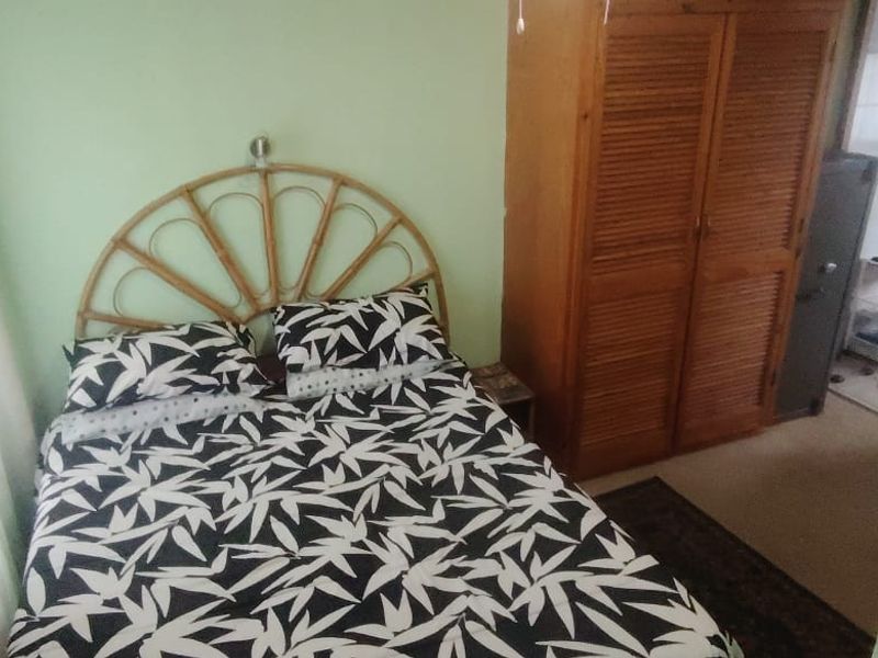 A bedroom featuring a built-in wooden wardrobe and access to an adjoining space.