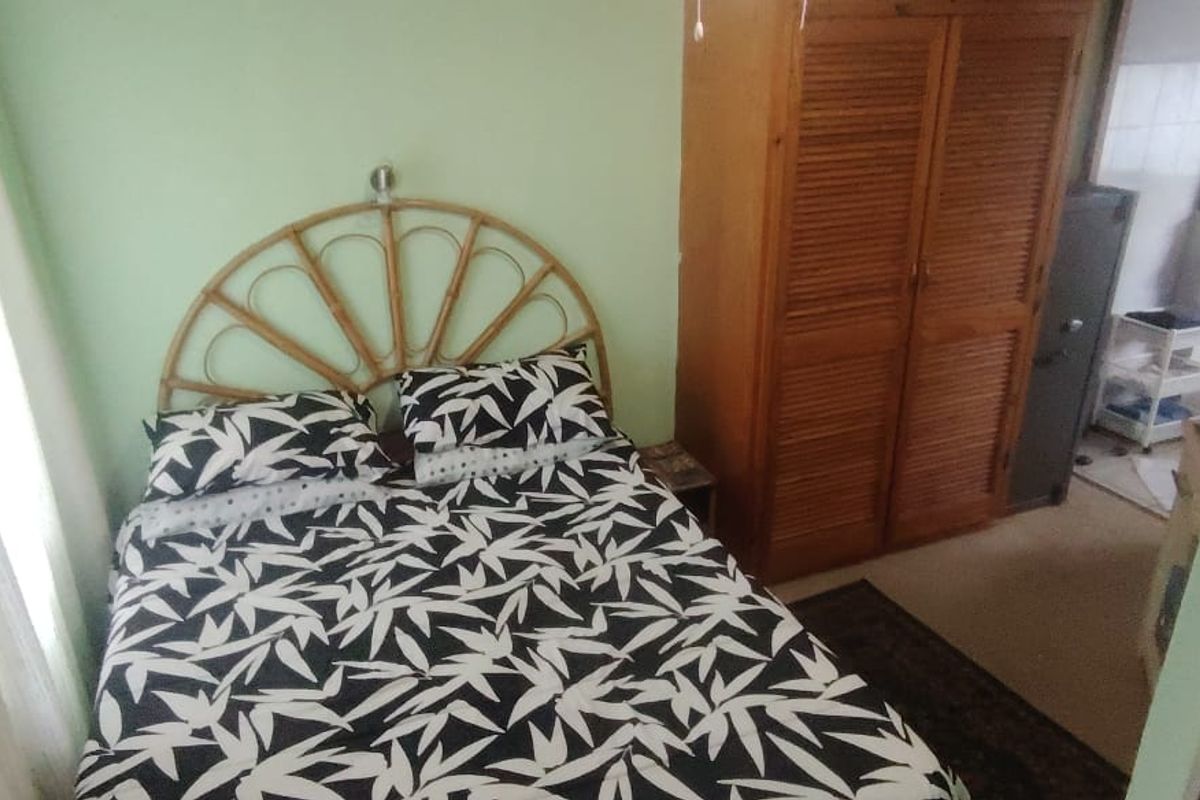 A bedroom featuring a built-in wooden wardrobe and access to an adjoining space.