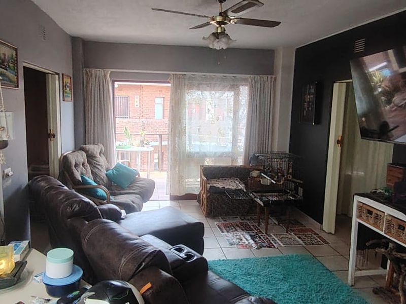 A living room featuring tiled flooring, a ceiling fan, and a sliding glass door providing access to an outdoor area.