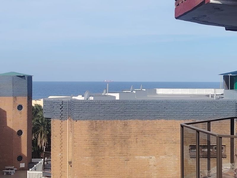 An elevated view overlooking the surrounding townhouse complex architecture with a clear horizon line of the ocean in the distance.