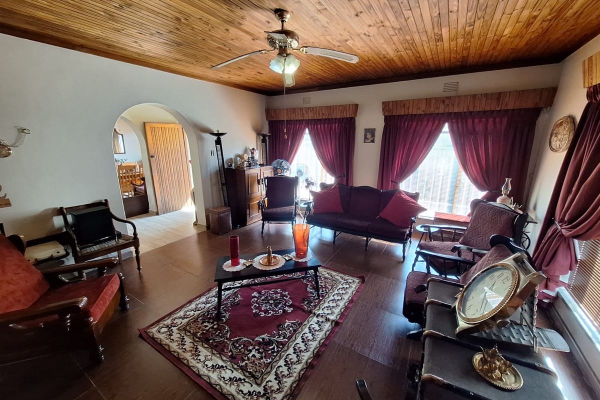 Spacious living room featuring a warm timber tongue and groove ceiling, tiled flooring, and an elegant arched doorway leading to adjacent areas.