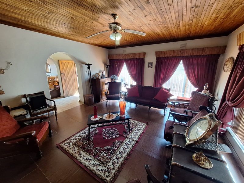 Spacious living room featuring a warm timber tongue and groove ceiling, tiled flooring, and an elegant arched doorway leading to adjacent areas.