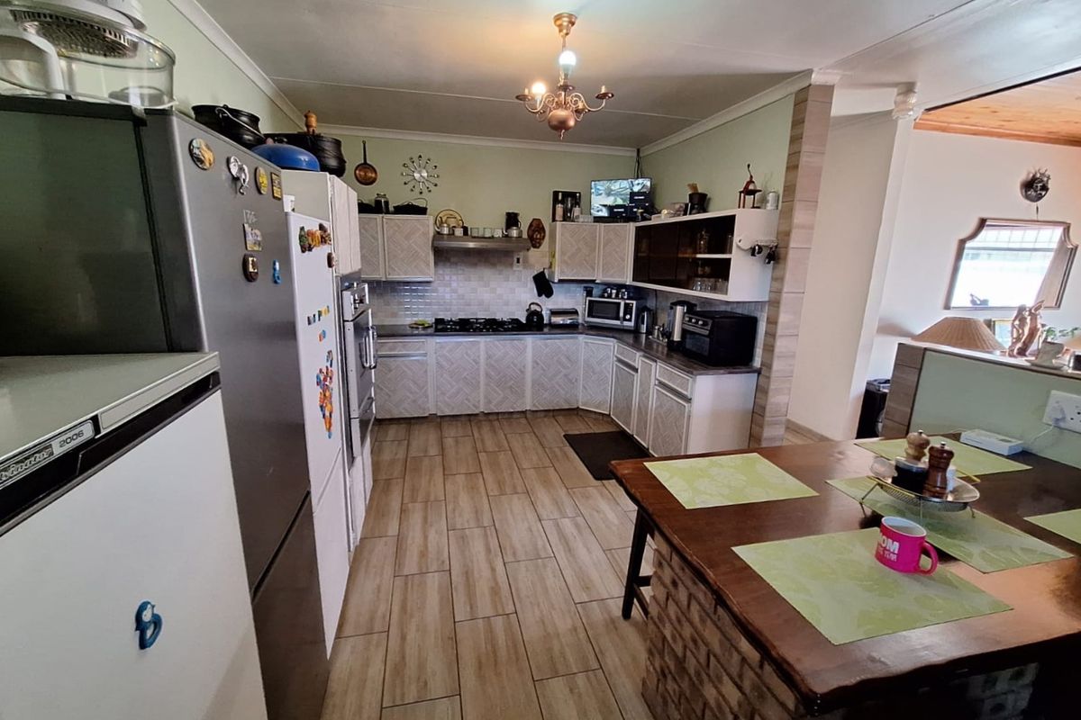 A functional kitchen featuring built-in cabinetry, a gas hob with extractor fan, tiled backsplash, and a breakfast counter with tiled flooring throughout.