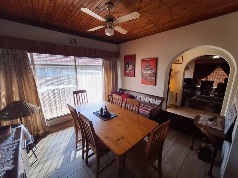 Dining room featuring a timber ceiling with a ceiling fan, tiled flooring, and an arched entryway leading to an adjacent living space.