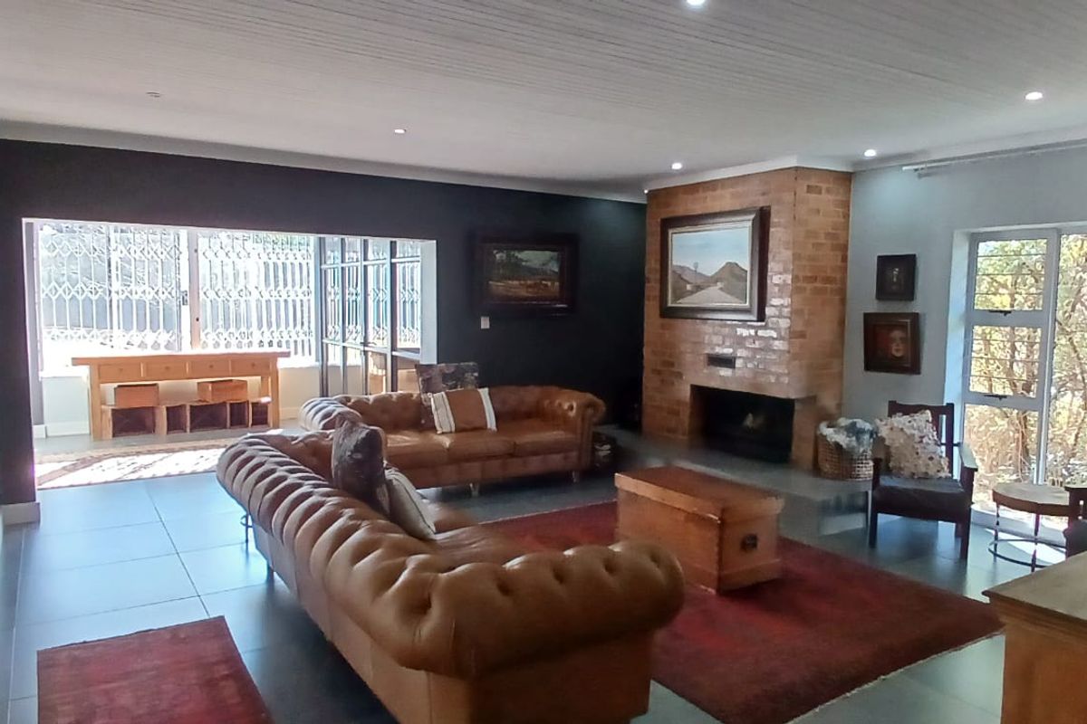 Spacious living room featuring a prominent brick fireplace, tiled flooring, and large sliding glass doors that provide access to the outdoor area.