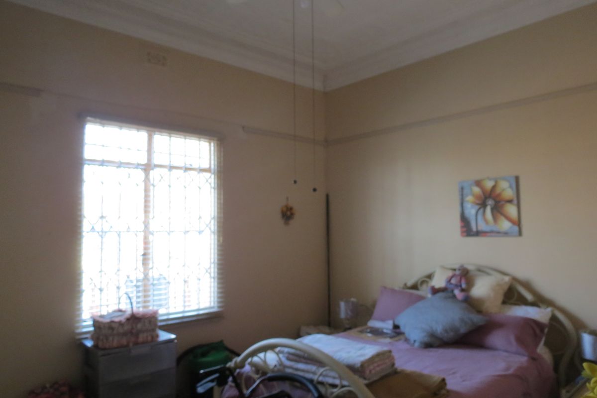 A bedroom featuring a ceiling fan, decorative cornice, picture rail, and window security bars.
