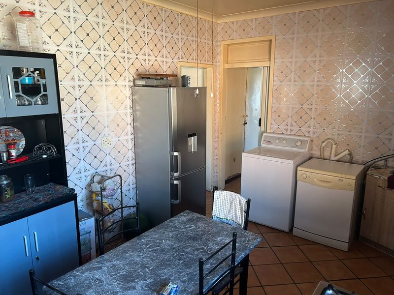 A functional kitchen area featuring tiled walls and flooring, providing a practical space for meal preparation and laundry utility.