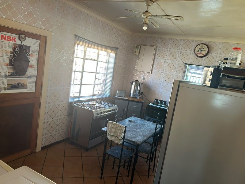 A dated kitchen featuring tiled flooring, a gas stove, and built-in cabinetry, offering potential for a modern renovation.