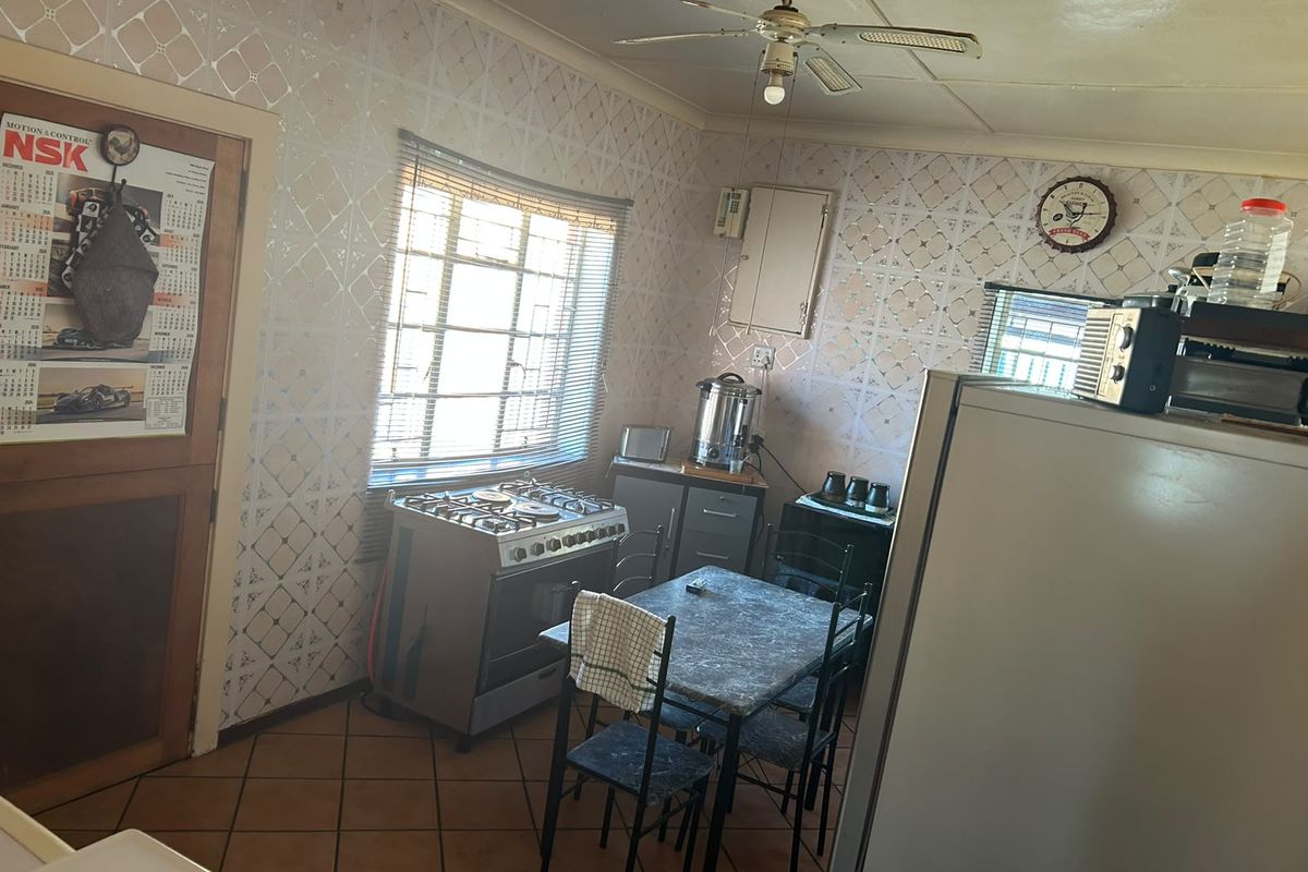 A dated kitchen featuring tiled flooring, a gas stove, and built-in cabinetry, offering potential for a modern renovation.