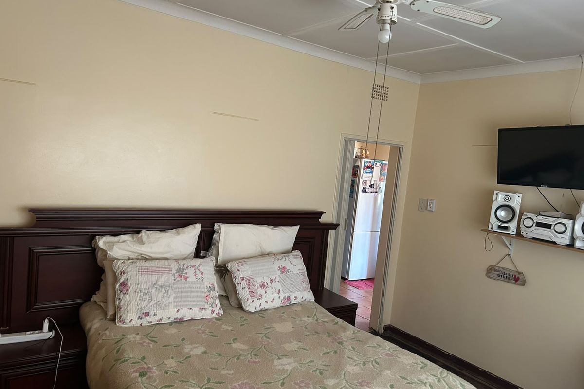A bedroom featuring a ceiling fan and coved cornicing, requiring cosmetic updates to the wall finishes and flooring to improve its overall condition.