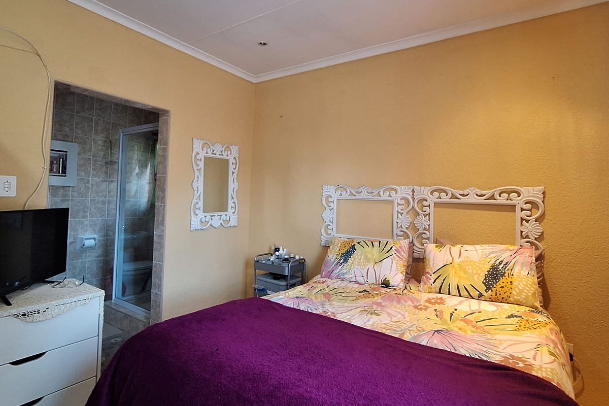 A bedroom featuring an en-suite bathroom, coved ceilings, and recessed lighting, offering a functional layout with potential for cosmetic updates.