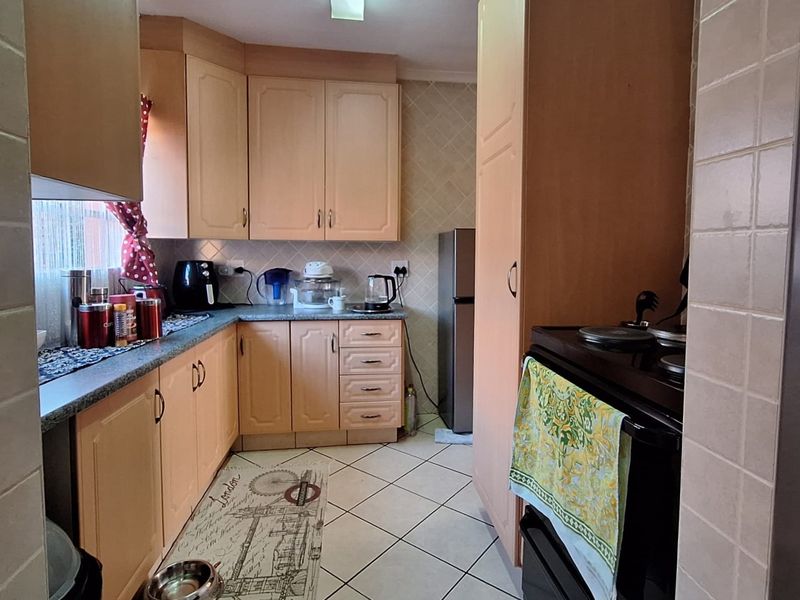 A functional kitchen featuring laminate cabinetry, tiled flooring, and a built-in oven, offering a practical layout with potential for modern cosmetic updates.