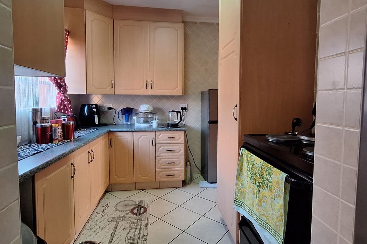 A functional kitchen featuring laminate cabinetry, tiled flooring, and a built-in oven, offering a practical layout with potential for modern cosmetic updates.