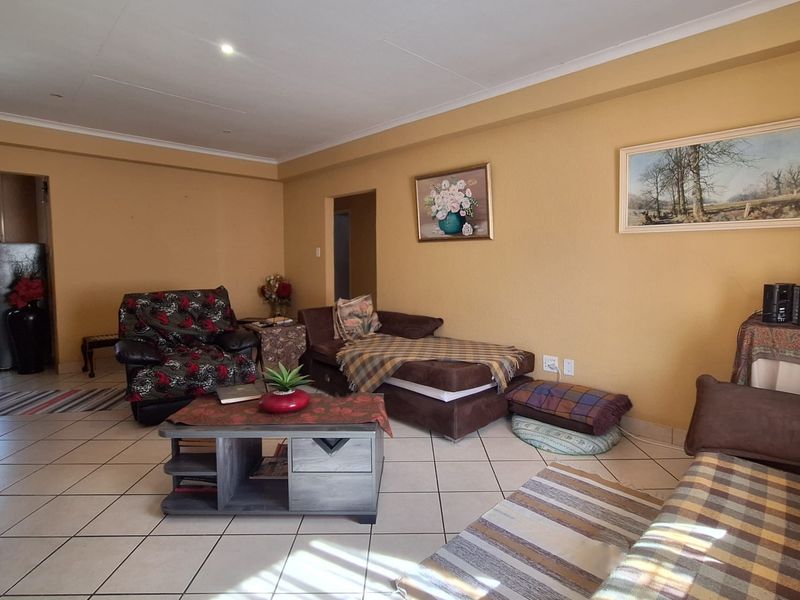 Spacious living room featuring neutral tiled flooring, recessed downlighting, and coved ceilings, offering a functional layout for comfortable family living.
