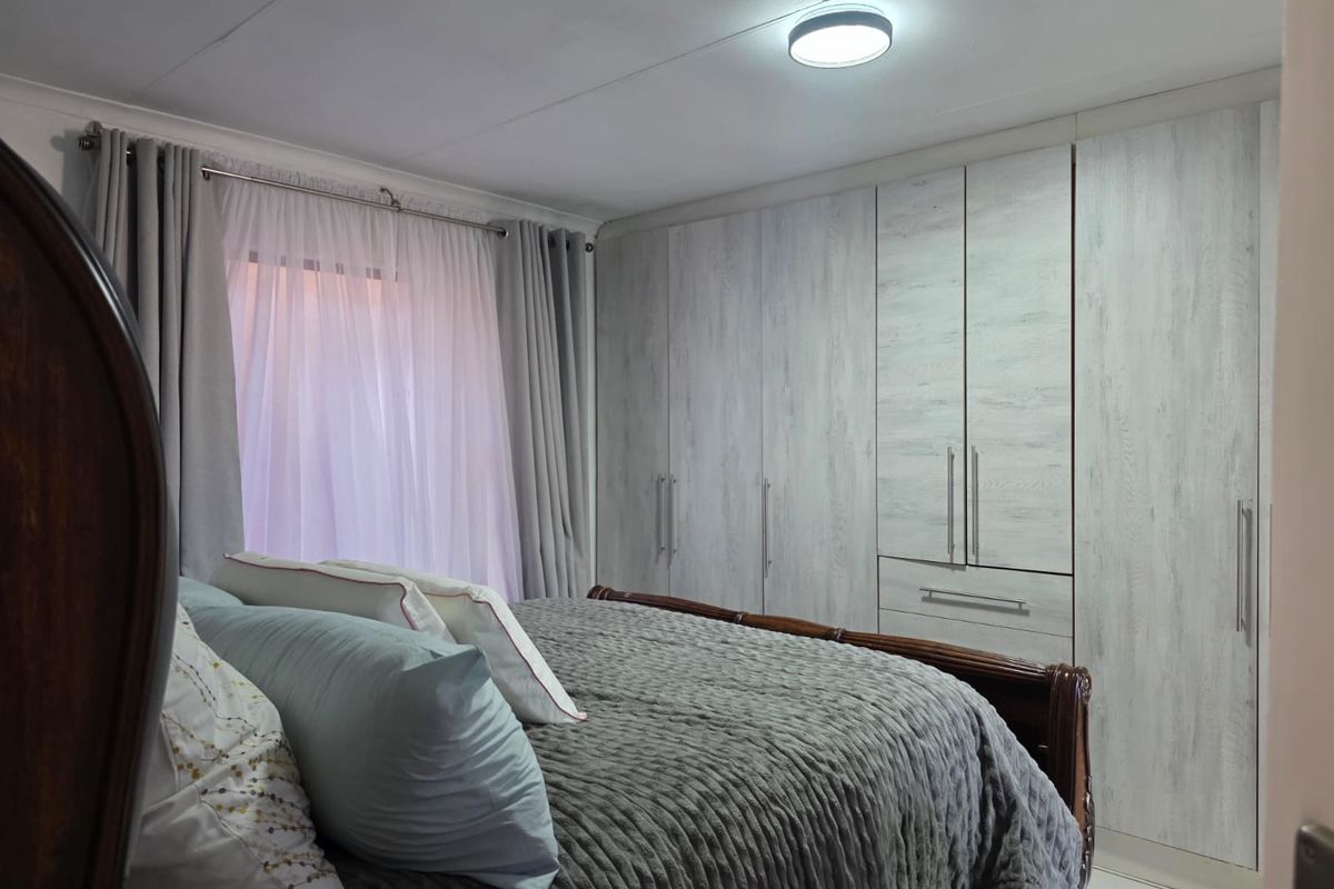 A well-maintained bedroom featuring modern light-wood grain built-in cupboards and a neutral color palette.
