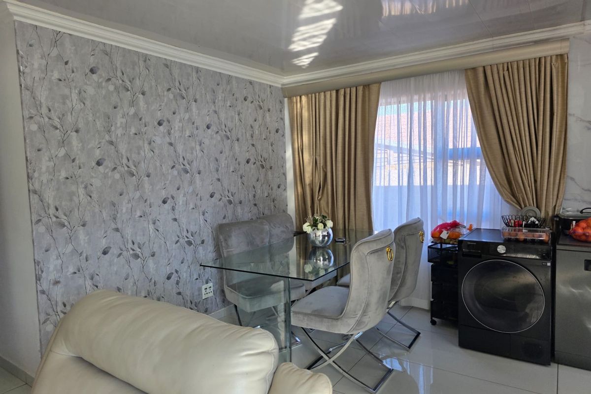 A living area featuring glossy floor tiles, coved ceiling detailing, and a decorative patterned feature wall.