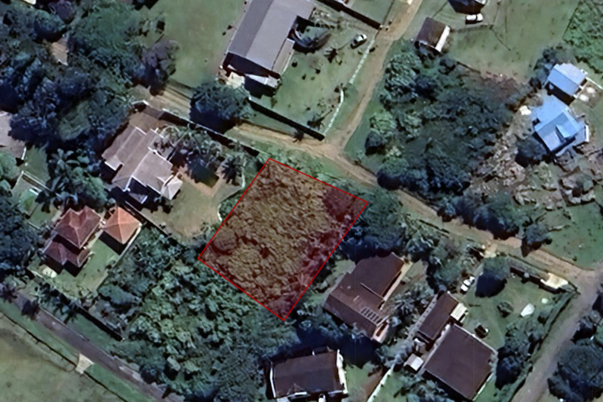 An aerial view of a vacant residential plot highlighted in red, situated within an established neighborhood.