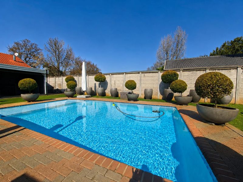 A well-maintained outdoor swimming pool area featuring brick paving and a secure perimeter wall, ideal for recreation and outdoor entertainment.