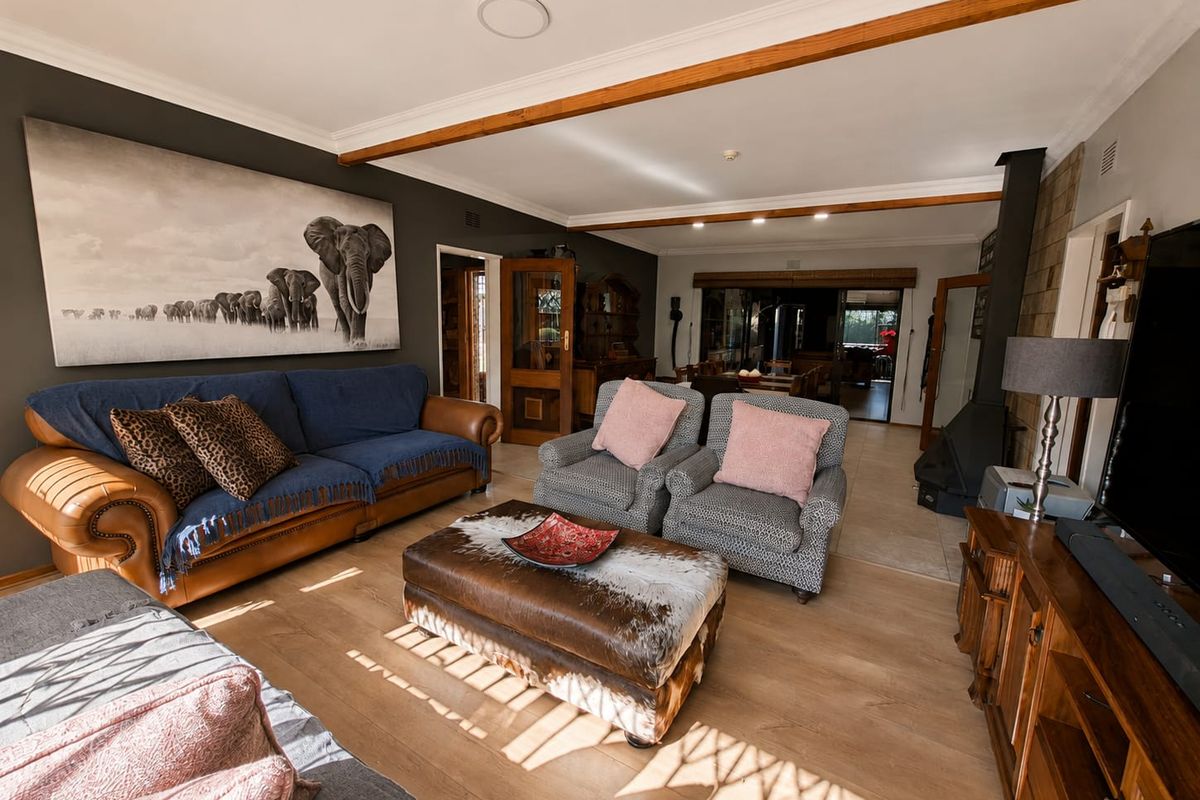 Spacious living room featuring exposed timber ceiling beams, laminate flooring, and a built-in wood-burning fireplace, creating a warm and inviting atmosphere.