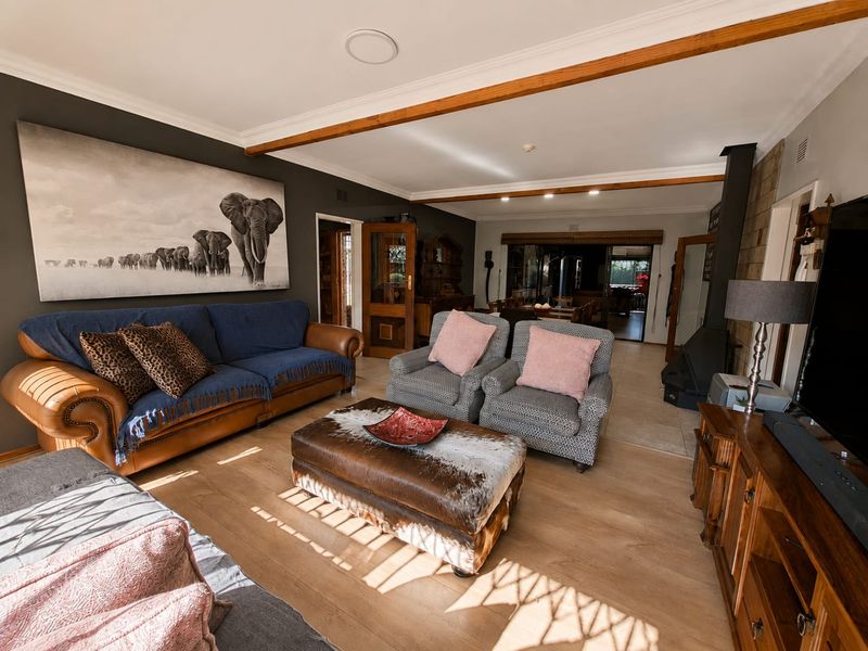 Spacious living room featuring exposed timber ceiling beams, laminate flooring, and a built-in wood-burning fireplace, creating a warm and inviting atmosphere.