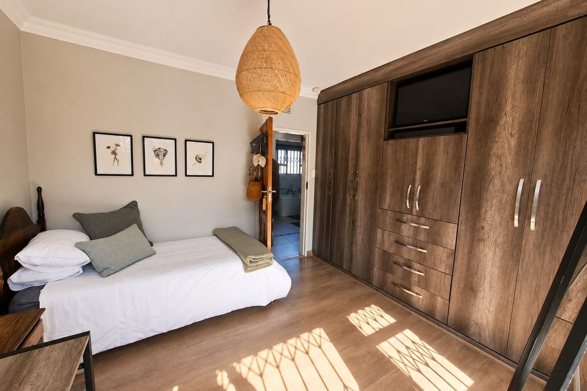 A well-maintained bedroom featuring extensive built-in wooden cabinetry, laminate flooring, and neutral wall finishes, with direct access to an adjoining bathroom.