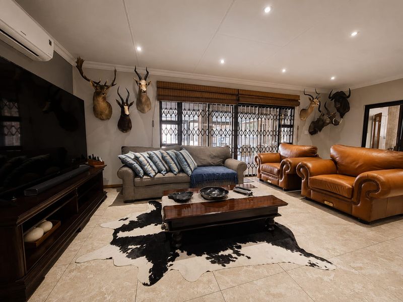 A spacious living room featuring tiled flooring, recessed downlighting, and a wall-mounted air conditioning unit, with secure access to the outdoor area.