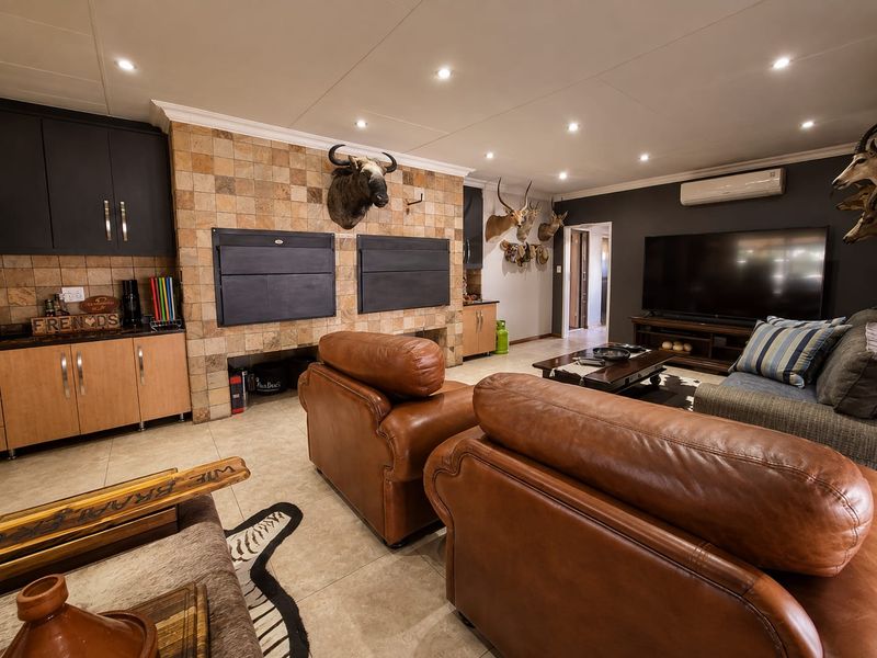 Spacious living area featuring a dual built-in braai with tiled surround, recessed lighting, and split-system air conditioning.