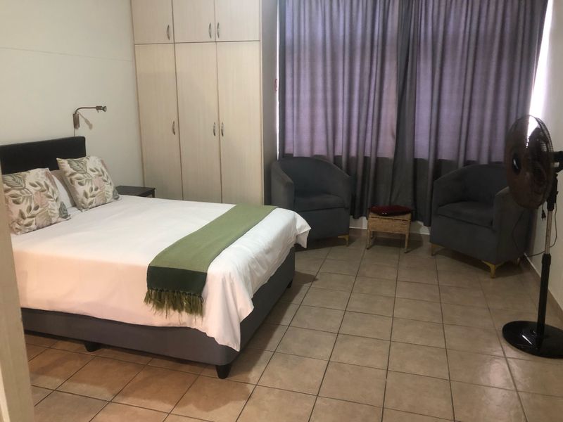 A functional bedroom featuring built-in cupboards, tiled flooring, and a wall-mounted reading light, offering a practical and comfortable living space.