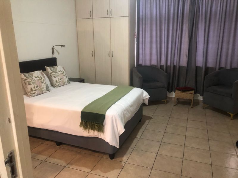 A bedroom featuring tiled flooring, built-in cupboards, and a wall-mounted reading light.
