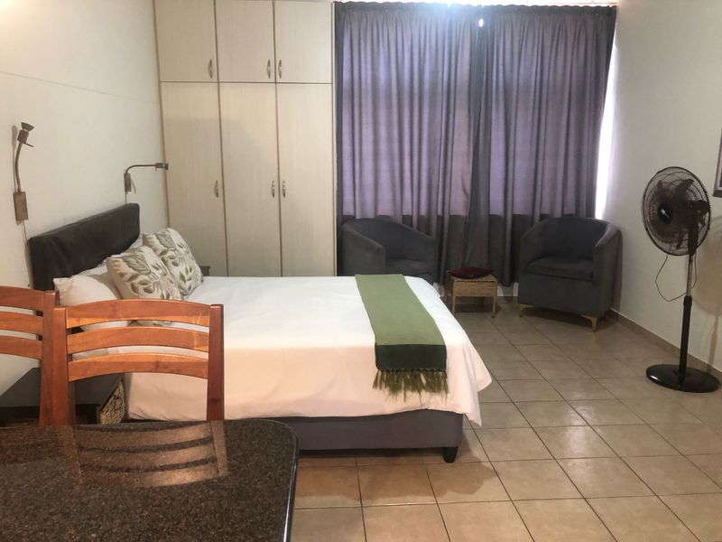 A functional bedroom featuring built-in cupboards, tiled flooring, and wall-mounted lighting fixtures.