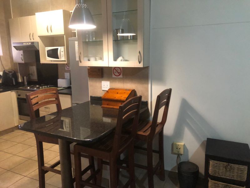 Compact kitchen featuring built-in cabinetry, granite countertops, and integrated appliances, including an oven, hob, and extractor fan.