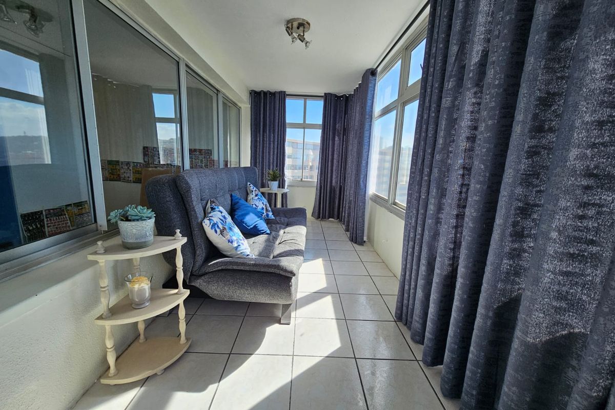 A bright, enclosed balcony featuring tiled flooring and expansive windows, offering a versatile space with natural light.