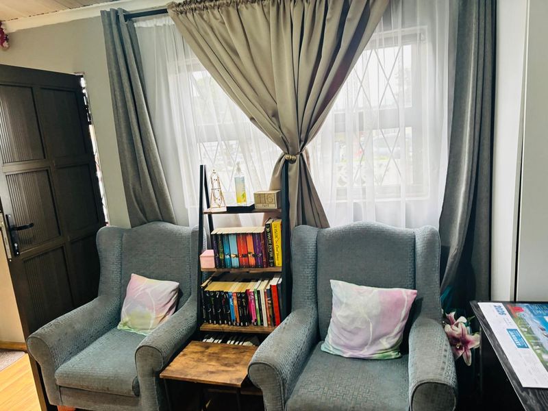 A cozy living area featuring laminate flooring, a window with security bars, and a solid timber door.