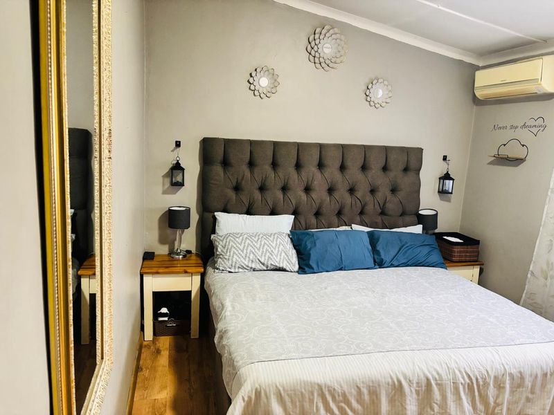 A cozy bedroom featuring laminate flooring and a wall-mounted split-system air conditioning unit.