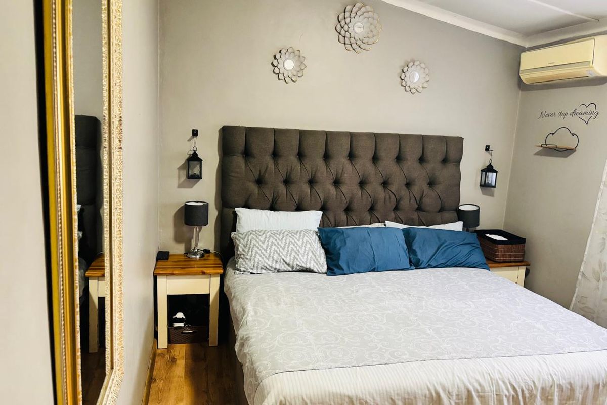 A cozy bedroom featuring laminate flooring and a wall-mounted split-system air conditioning unit.