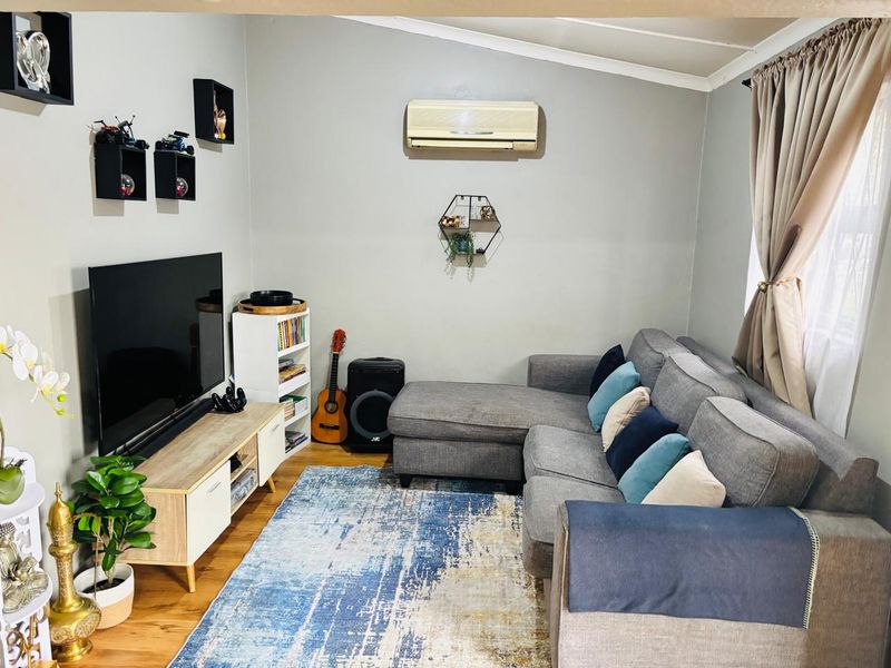 A cozy living room featuring laminate flooring and a wall-mounted split-system air conditioner unit.