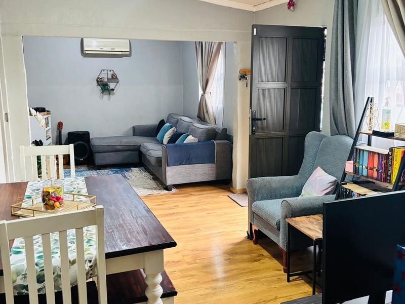 Open-plan living and dining area featuring laminate flooring, timber ceiling, and a wall-mounted air conditioning unit.