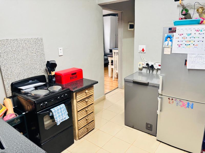 A functional kitchen area featuring a freestanding stove, granite countertops, and tiled flooring, with a doorway leading to an adjacent room.