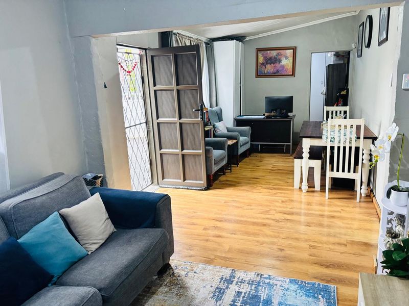 Open plan living and dining area featuring laminate flooring and direct access to the exterior through a security gate and timber door.