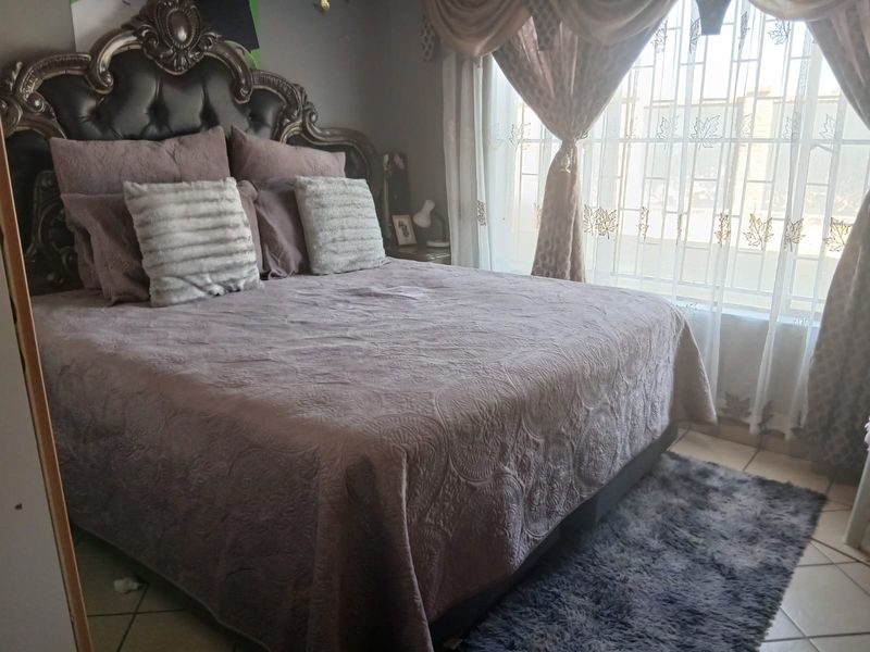 A bedroom featuring tiled flooring and window security bars, providing a functional and secure sleeping space.