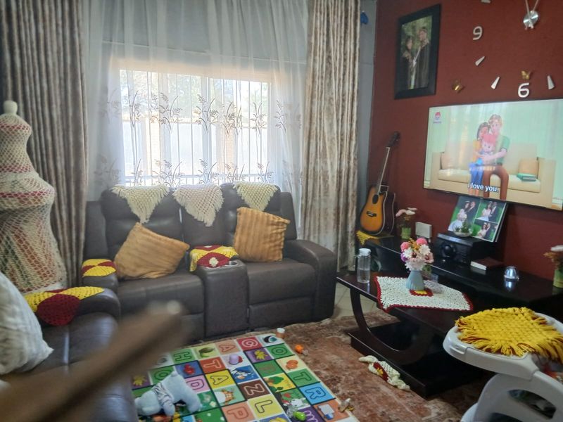 A cozy living room featuring a large window with security bars and curtain rails, providing a comfortable space for relaxation.