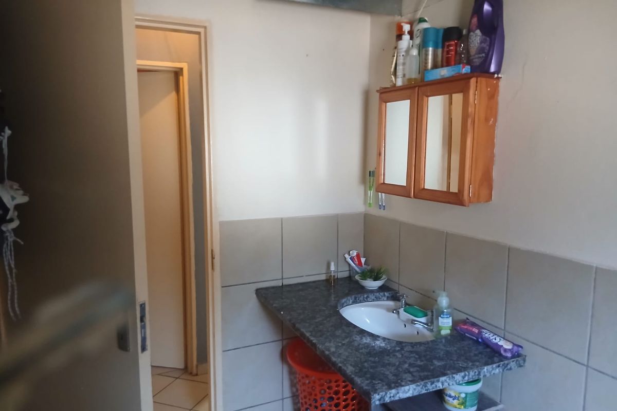 A compact bathroom featuring a vanity basin with a tiled splashback and a wall-mounted medicine cabinet.