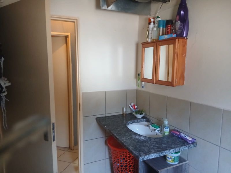 A compact bathroom featuring a vanity basin with a tiled splashback and a wall-mounted medicine cabinet.